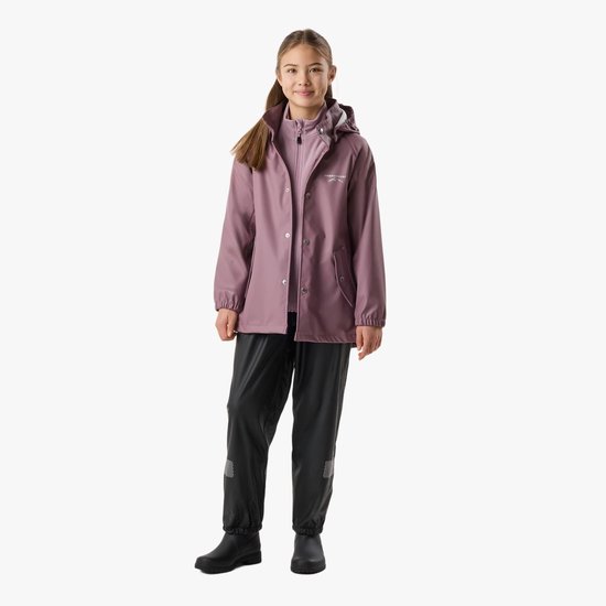 Meisje met lang bruin haar draagt een lichtroze regenjas en zwarte regenbroek.