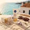 Nivea Sun Spot Control SPF 50+ gezichtszonnebrandcrème, verpakking en zonnebril op een handdoek met uitzicht op zee.