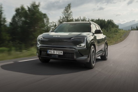 Donkergroene SUV rijdt op een landweg door een bosrijk gebied, gefotografeerd vanaf de voorkant.
