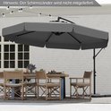 Grijze zweefparasol die een buitentafel met stoelen en een eettafel bij een huis dekt.