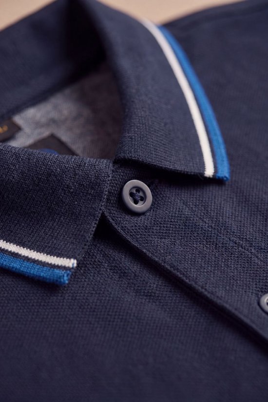Detail van de knoopsluiting en de gestreepte kraag van een marineblauwe poloshirt.