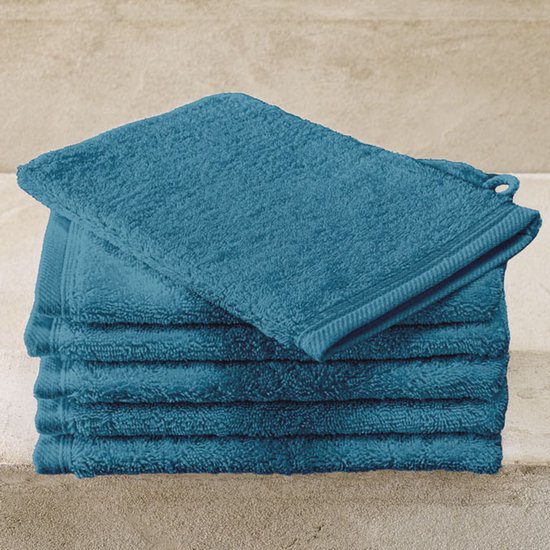 Stapel blauwe washandjes op een stenen ondergrond.