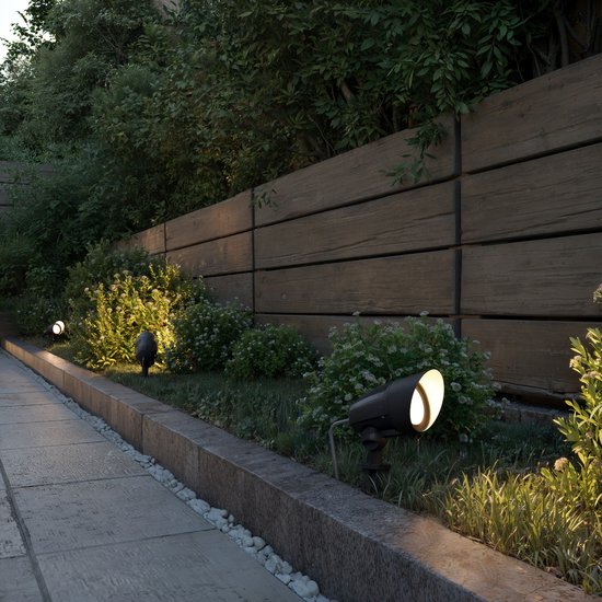 Zwarte prikspots verlichten een tuinpad langs houten schutting.