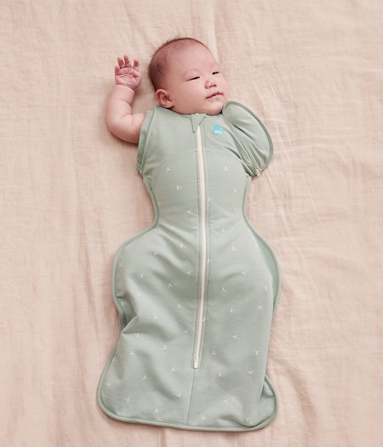 Baby in sagegroene slaapzak met takjesprint en rits, één arm naar buiten.