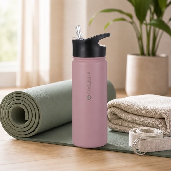Roze 500ml drinkfles met zwarte rietjesdop op een yogamat, naast handdoek.