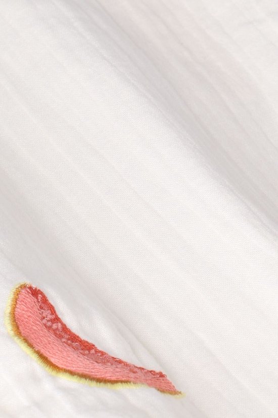 Detail van gebroken witte stof met roze geborduurde veer.