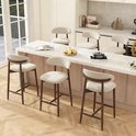 Set van vijf beige barkrukken met houten poten en rugleuning bij een keukenbar.