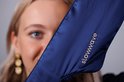 Een vrouw met blond haar draagt een donkerblauw zijden slaapmasker van Slowwave.