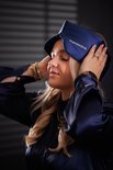 Een vrouw met blond haar met gesloten ogen draagt een donkerblauw zijden slaapmasker van Slowwave.