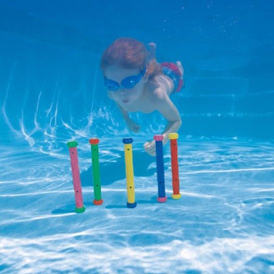 Een jongen met een zwembril duikt onder water naar vijf felgekleurde duikstokjes op de bodem van een zwembad.