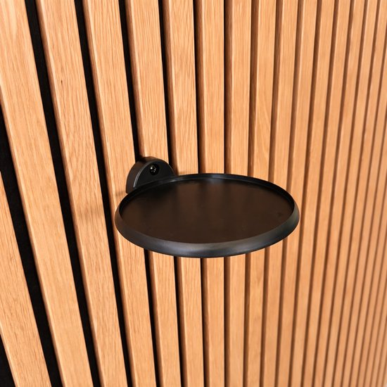 Zwart rond plateau met een diameter van 14cm, bevestigd aan een houten lamellenwand.