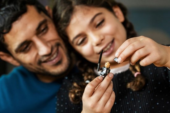 Vader en dochter kijken lachwekkend naar een LEGO minifiguur met zwaard.