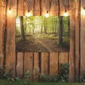 Decoratieve poster van een bos met pad, opgehangen aan een houten schutting met lichtslingers.