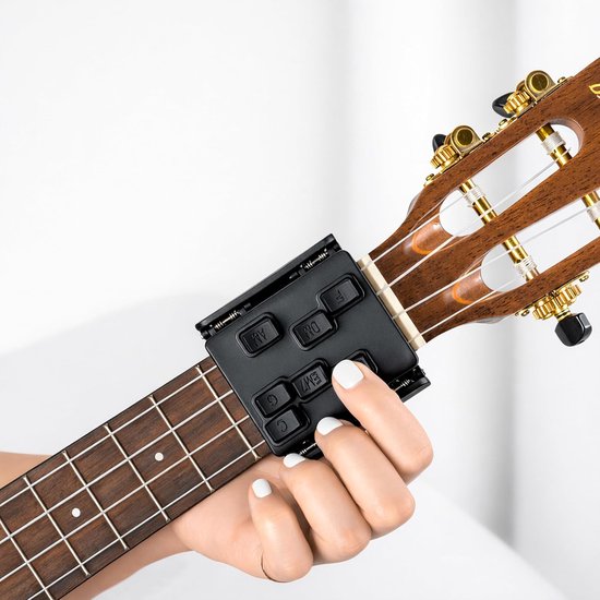 Zwarte akkoordhulp met knoppen voor C, F, Am, Dm, Em7, G, G7, bevestigd aan de hals van een ukelele.