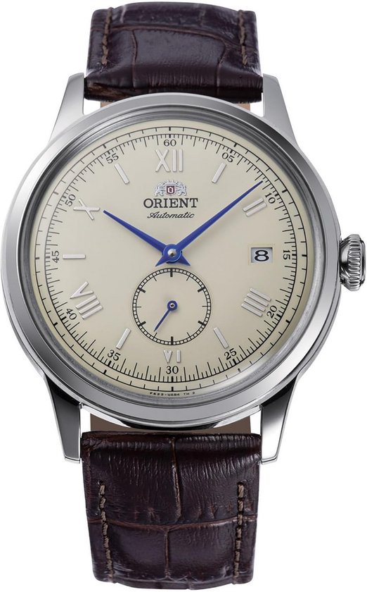 Oriënt horloge met crème wijzerplaat, Romeinse cijfers, datumvenster en kleine secondewijzer op bruin lederen band.