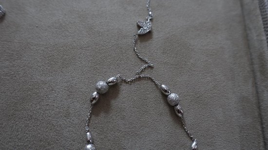 Zilverkleurige armband met vlinderbedel en gepolijste en glitterbolletjes.