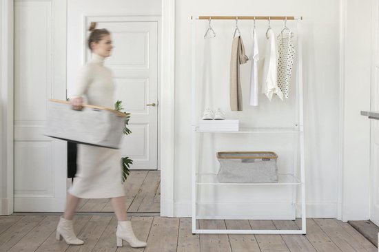 Vrouw met grijze wasmand met bamboe frame, lopend bij een kledingrek.