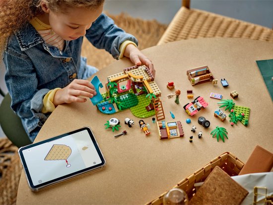 Meisje speelt met de LEGO Friends Pandaopvang set, quad en losse onderdelen op tafel.