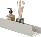 Een beige wandrek met een zeepdispenser en een fles met geurstokjes.