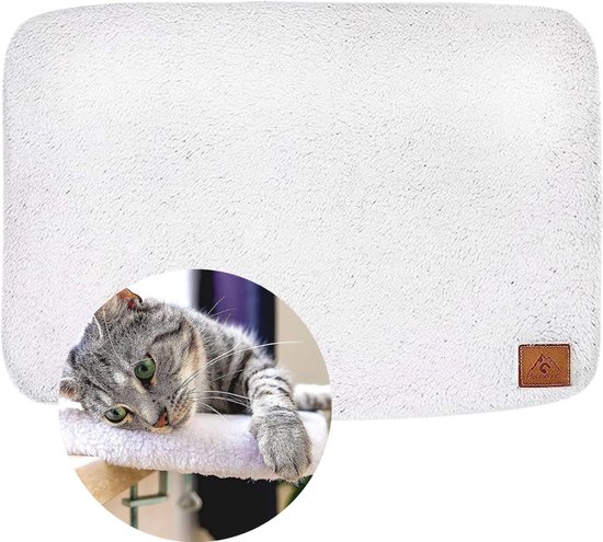 Close-up van een witte pluche kattenmat met een schattige grijze kat met groene ogen die erop rust.