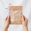 Een handen houden een oranje stickerboek met een capybara-thema, getiteld 'CAKE SHOP'. Afmetingen 11x15cm. Gedetailleerde illustratie van een drukke bakkerij met capybara's.