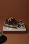 Donkerbruine suède sneakers met bontvoering, gepresenteerd op een platenspeler.
