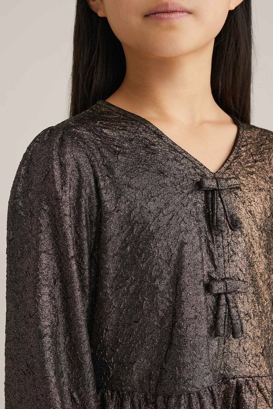 Detail van bruin metallic peplum T-shirt met strikdetail.