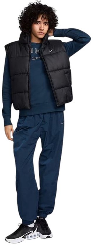 Volledige outfit met zwarte Nike bodywarmer, blauw Nike sweatshirt, blauwe Nike broek en zwarte sneakers.