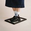 Model draagt een spijkerrok en zwarte klomp-sneakers met witte sokken met berglandschap.