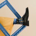 Model draagt een gele broek, een zwarte loafer en een sok met Van Goghs Sterrennacht.