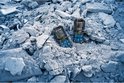 Twee Bosch laser afstandmeters liggen tussen puin. De afstandmeters zijn robuust en hebben een zwart met blauwe behuizing.