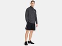 Man in zwart sportshirt met halve rits en zwart sportbroekje met logo op linkerbeen.