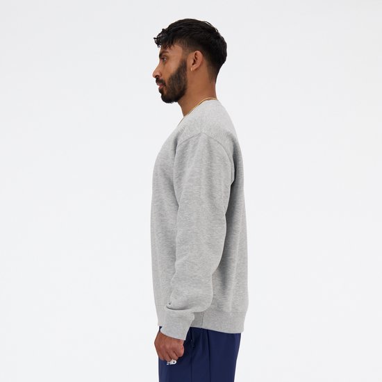 Man van opzij in grijze New Balance sweater met wit logo.