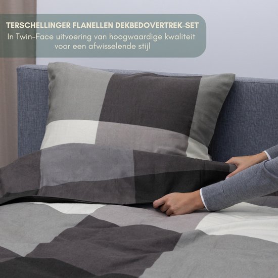 Dekbedovertrekset met blokpatroon van grijs, bruin en crème, met handen die het leggen.