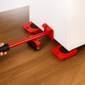 Rode meubelrollers en hefstang onder een wit meubelstuk op een houten vloer.