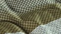 Gros plan d'une housse de couette verte avec un motif subtil et répétitif de petits carrés marron.
