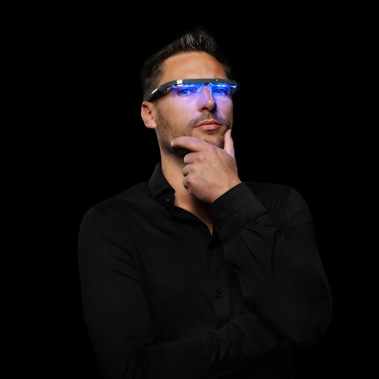 Man met zwart overhemd, denkend met een lichttherapiebril met blauw licht op.