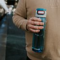 Homme en pull beige tenant une bouteille Kambukka bleue.