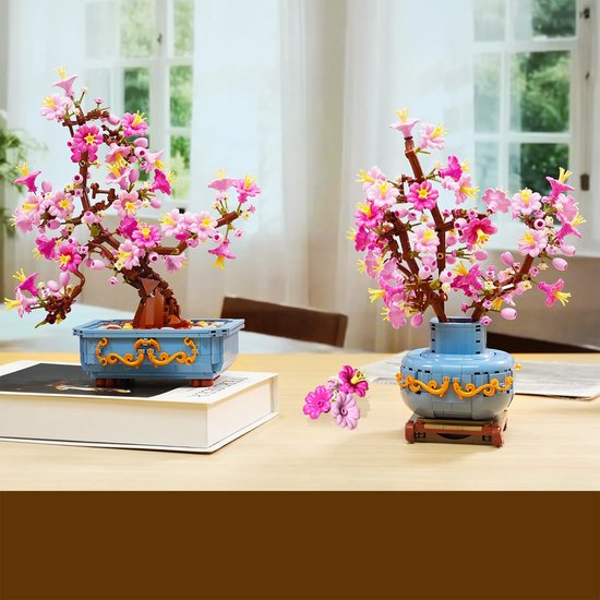 Bonsaï de fleurs de cerisier roses dans un pot bleu à côté d'un bouquet de fleurs de cerisier roses dans un vase bleu.