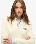 Close-up van een off-white, halve rits trui met kraag en een Amerikaanse vlag badge op de linkerborst.