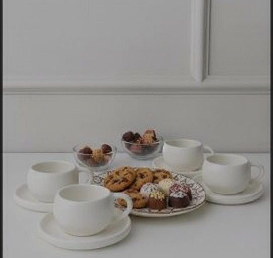 Drie witte mokken met schotels, rondom een bord met koekjes en kleine gebakjes, en twee schaaltjes met snoepjes.