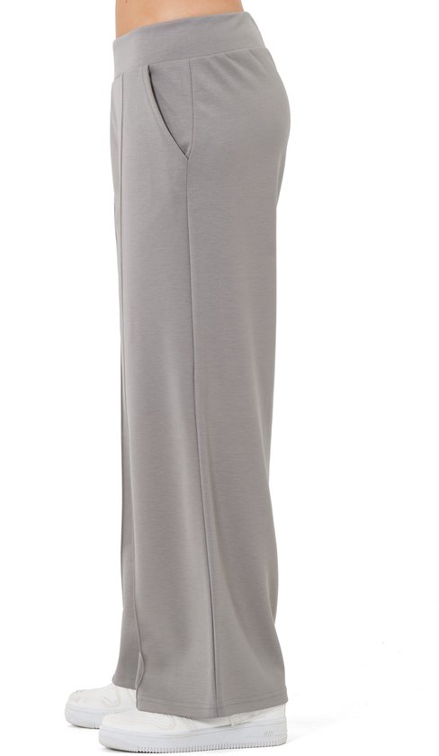 Zijkant van een grijze joggingbroek met rechte pijp en zakken, gedragen door een model.