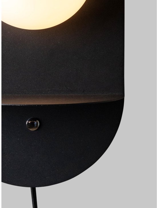 Close-up van een zwarte wandlamp met een aan/uit schakelaar op het schapje.