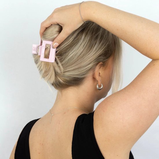 Roze acetaat haarklem in een opgestoken kapsel, met een zilverkleurige ketting.