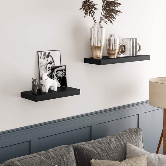 Zwarte zwevende planken in een woonkamer met decoraties en boeken.