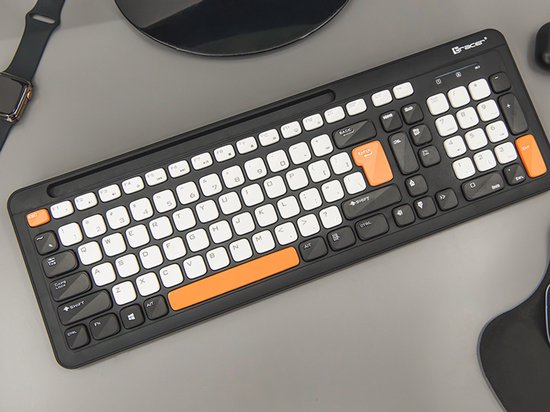 Zwart toetsenbord met witte en oranje toetsen, liggend op een grijze ondergrond. Met oranje spatiebalk en enter-toets.