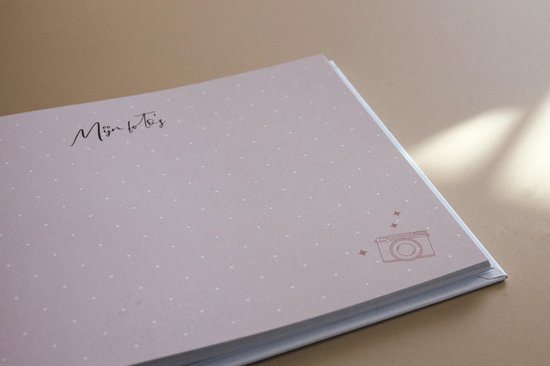 Een close-up van een open kraamvisiteboek met een roze achtergrond en witte polka dots. De tekst 'Mijn fotoboek' staat op de pagina.