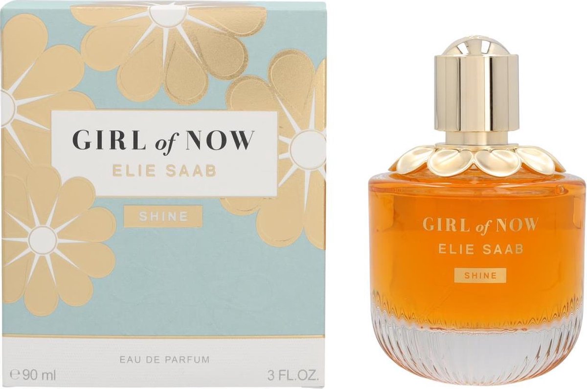Gouden parfumfles met gegolfde glazen bodem, gouden dop en bloemendecoratie. Tekst: GIRL of NOW, ELIE SAAB, SHINE.