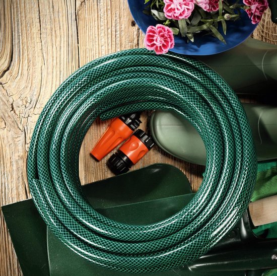 Groene tuinslang opgerold op een houten ondergrond, met oranje sproeiers, groene laarzen en een schop.