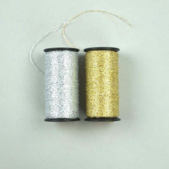 Twee spoelen met metallic garen, één zilverkleurig en één goudkleurig.